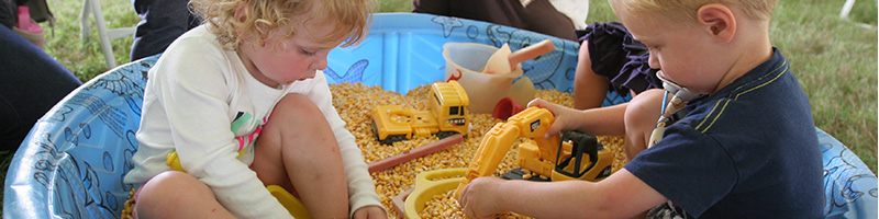 Young children playing with toys in a sand box