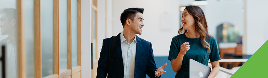 Two coworkers walking and talking in the office
