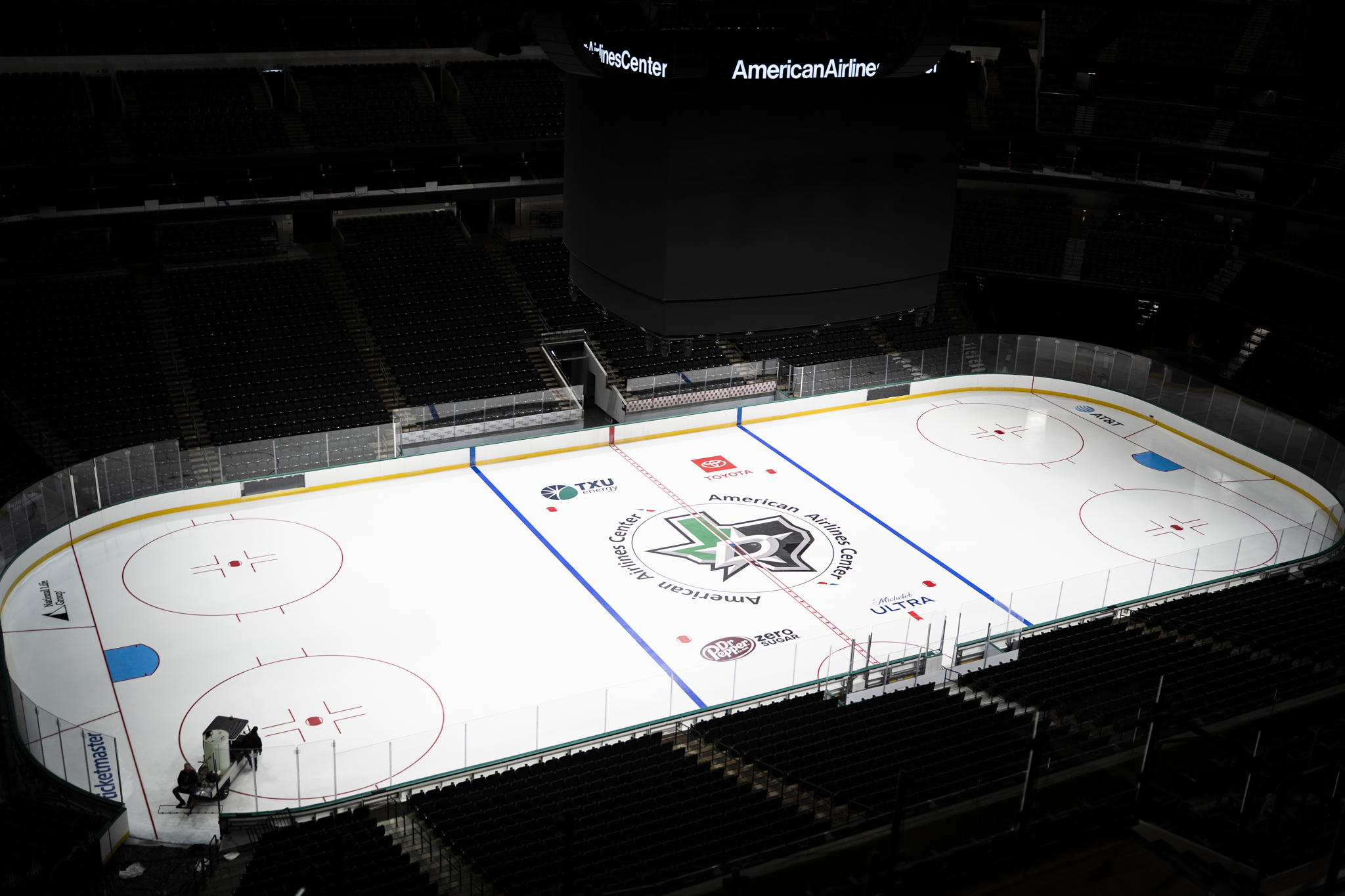 Two people working beside the National Life Group logo on the Dallas Stars hockey rink ice